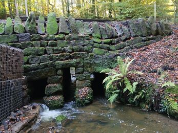 A drystone bridge over a stream in a woodland