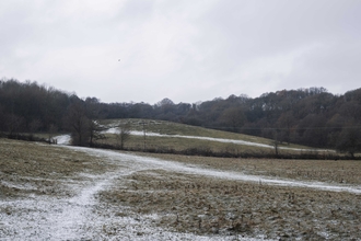 A countryside scene with rolling hills and some snow on the ground