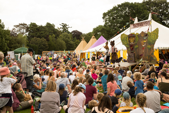 A crowd of people gather round to watch a performance on an outdoor stage