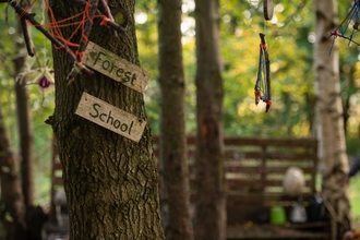 A rustic sign fixed to a tree trunk reads forest school