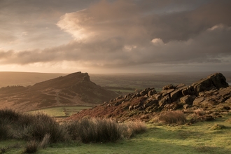 A dramatic rocky ridge landscape with dusky pink and grey clouds overhead