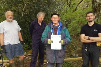 A group of volunteers gather round a man who has been presented an award