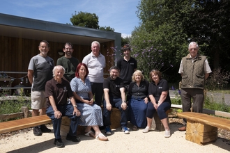 A group of people sit outside a new learning facility 