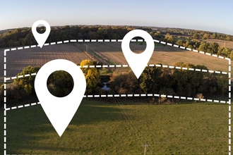 A landscape with woodland and grassland is overlaid with white dashed lines showing the boundaries and pin points