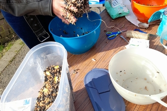 Someone moulding together seed and fat to make a bird feeder