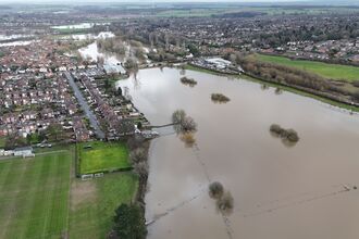 A aerial view of a nature reserve submerged in water near a community of homes.