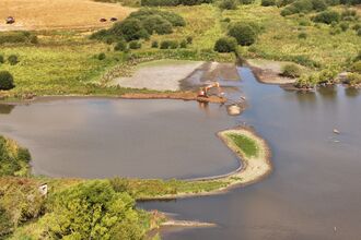 An aerial view of machinery working in a pool to create small islands