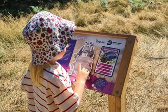 A young girl stands in front of a colourful display panel