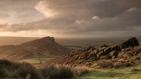A dramatic rocky ridge landscape with dusky pink and grey clouds overhead