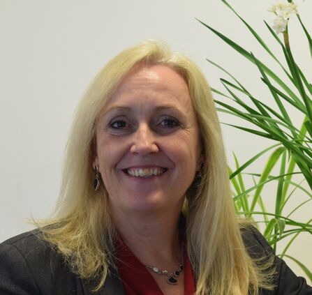 A photographic portrait of a woman standing in front of a plant