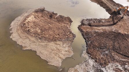 An aerial view of machinery working in a pool to create small islands