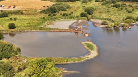 An aerial view of machinery working in a pool to create small islands