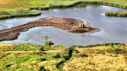 An aerial view of machinery working in a pool to create small islands