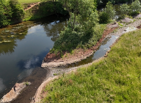 A aerial view of a river with a freshly dug channel and surrounding flora