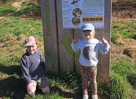 Two children on a nature reserve, wearing caps and sunglasses.